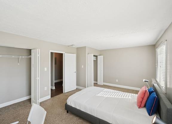 A bedroom with a bed, chair, and closet.