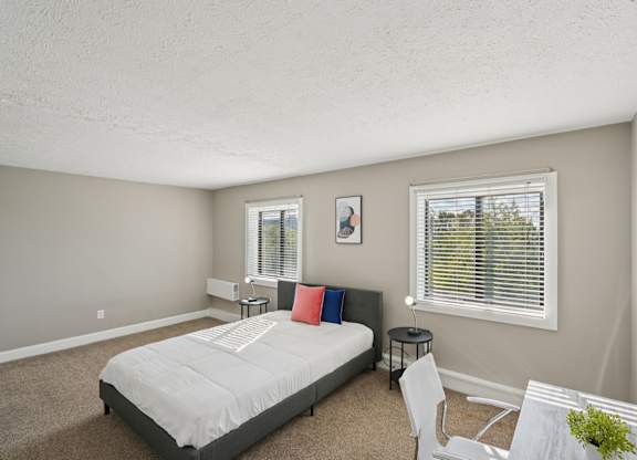 A bedroom with a bed, chair, and window.
