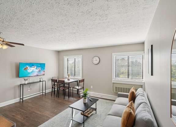 A living room with a grey couch and a painting on the wall.
