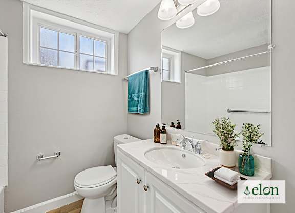 A bathroom with a white toilet, sink, and mirror.