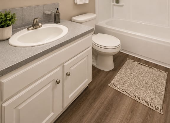 A bathroom with a white toilet, sink, and a mirror above the sink.