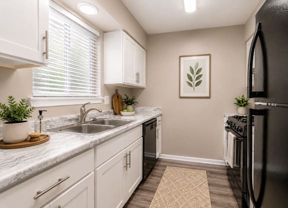 A kitchen with white cabinets and a black refrigerator.