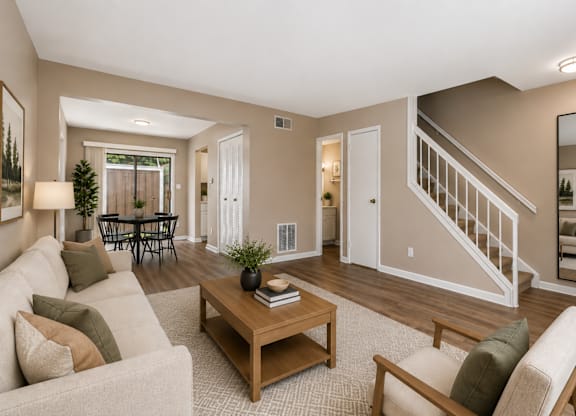 A living room with a white couch, a coffee table, and a staircase.