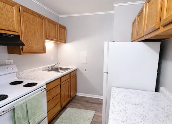 A kitchen with a white stove top oven and a white refrigerator.