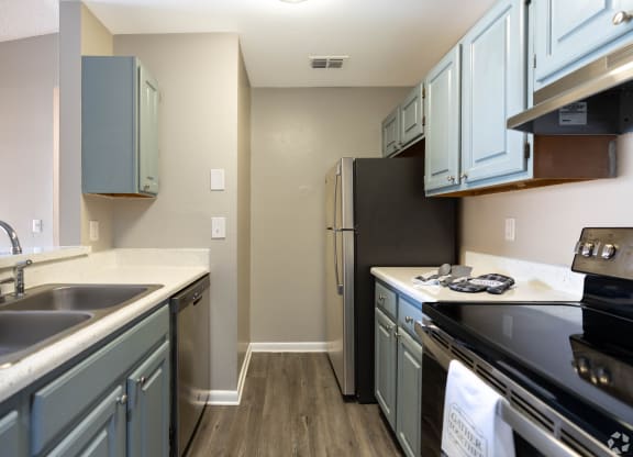 a kitchen with stainless steel appliances and blue cabinets at Aqua Bay Apartments in Naples, FL 34116