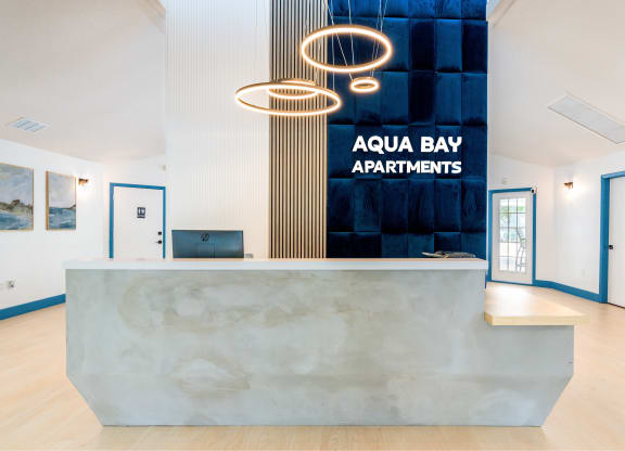 the front desk apartments with a marble reception desk and a sign at Aqua Bay Apartments in Naples, FL 34116