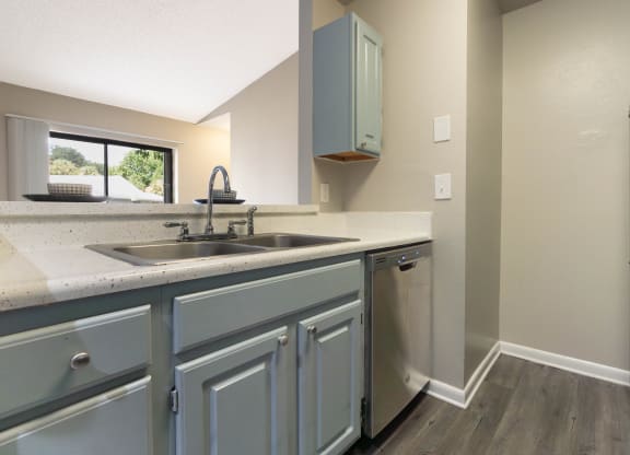 the kitchen of a home with stainless steel appliances and blue cabinets at Aqua Bay Apartments in Naples, FL 34116