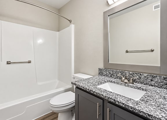 A bathroom with a white toilet and a marble countertop.
