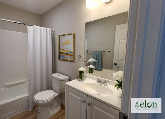 A white bathroom with a toilet, sink, and shower.
