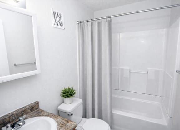 A white bathroom with a toilet, sink, and shower.