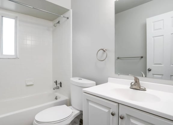A white bathroom with a toilet, sink, and bathtub.