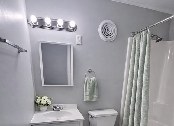 A white bathroom with a toilet, sink, and shower.