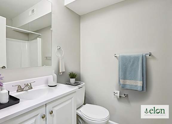 A white bathroom with a toilet, sink, and mirror.