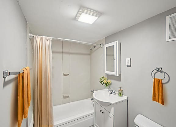 A bathroom with a white tub, sink, and towel rack.