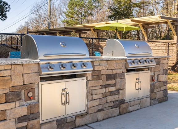 A wall of outdoor grills is built into a stone wall.