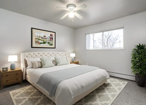 A bedroom with a large bed, a ceiling fan, and a potted plant.