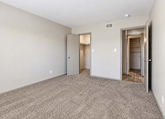 A room with carpeted floor and two open doors.