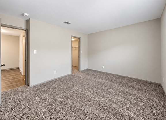 A room with a carpeted floor and two doors.