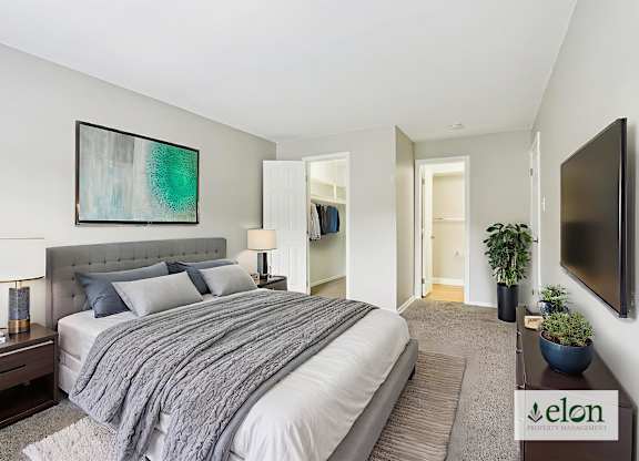 A bedroom with a large bed and a painting on the wall.