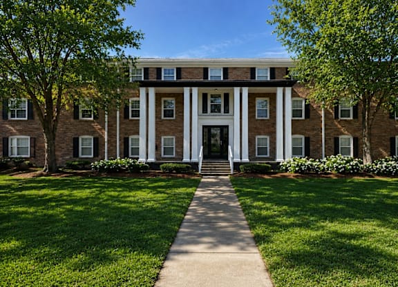 A building with a white front door flanked by two trees.