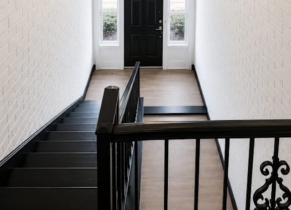 A black metal staircase with a black railing and a light hanging from the ceiling.