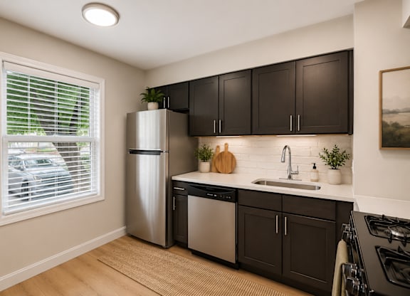 A kitchen with black cabinets and a stainless steel refrigerator.