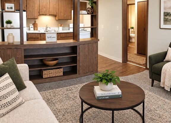 A living room with a couch, a coffee table, and a kitchen area in the background.