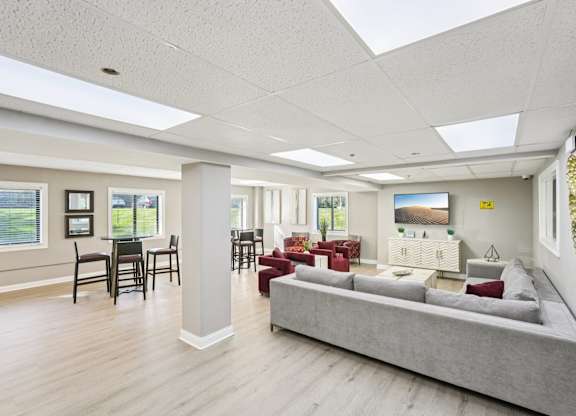 A spacious living room with a grey sofa and a dining table with chairs.