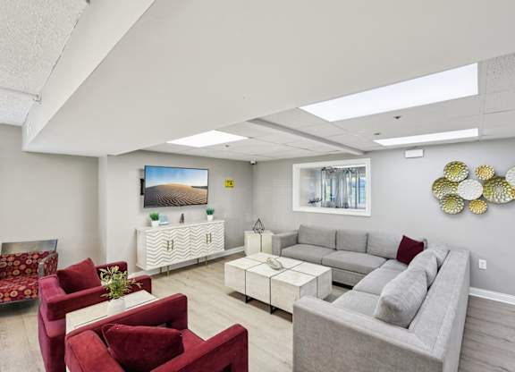 A living room with a grey couch, red armchair, and a white coffee table.