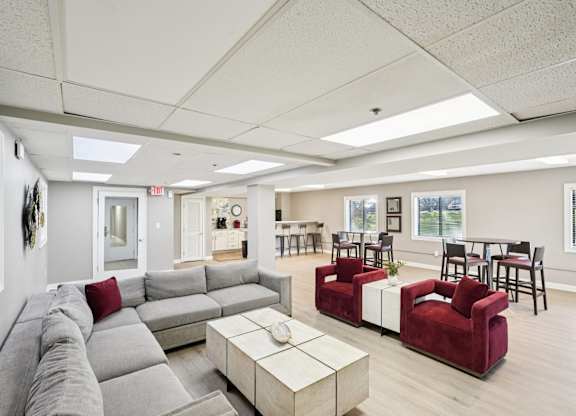 A living room with a grey couch and a red chair.