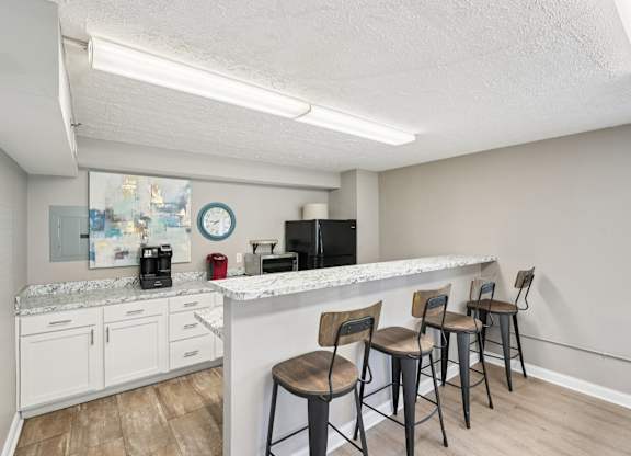 A kitchen with a white counter and chairs.