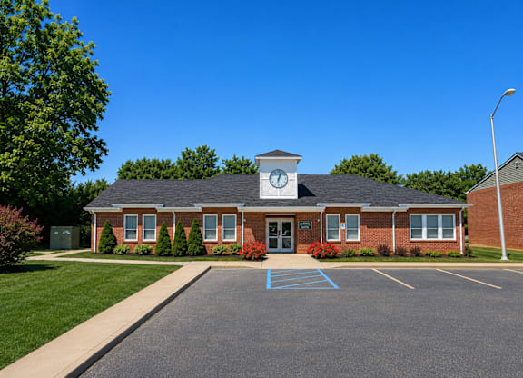 A building with a clock tower is surrounded by a parking lot.