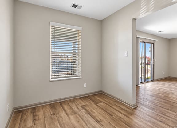 A room with wooden floors and a window with blinds.