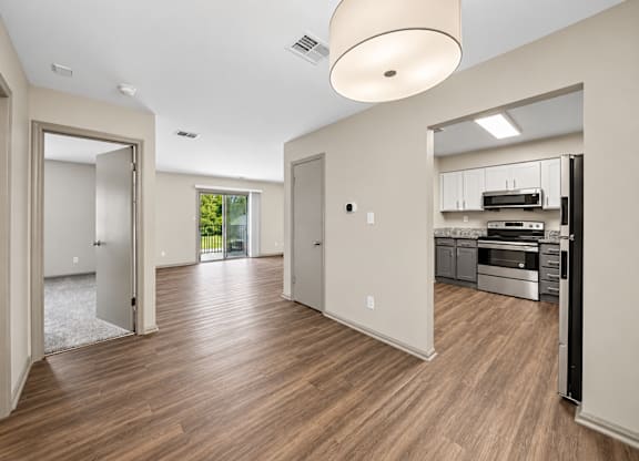 A spacious room with wooden floors and a kitchen area in the background.