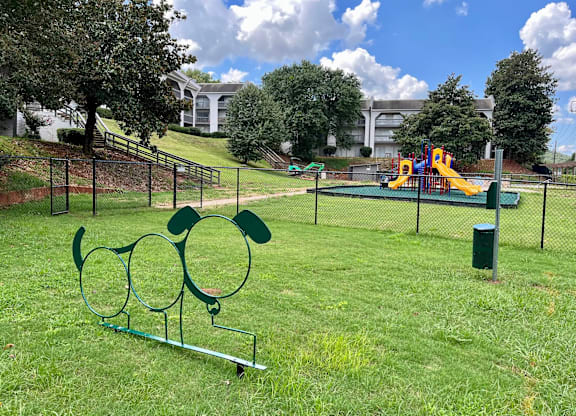 A playground with a slide and a green trash can.