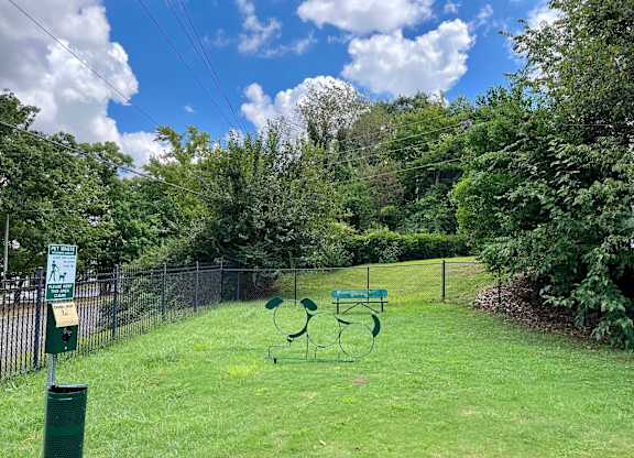 A green park bench sits in the middle of a grassy area.