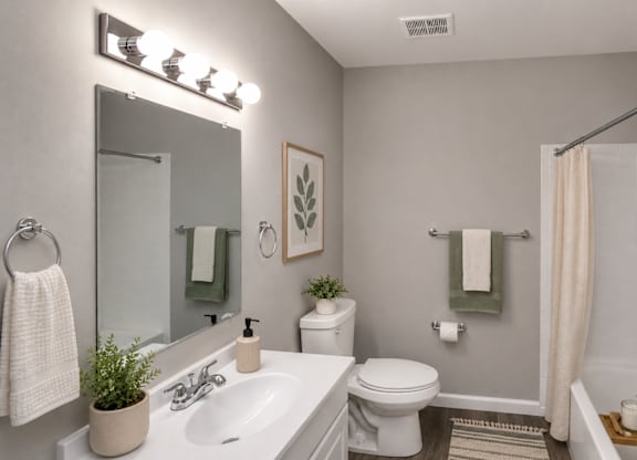 A bathroom with a white sink, toilet, and a mirror above them.