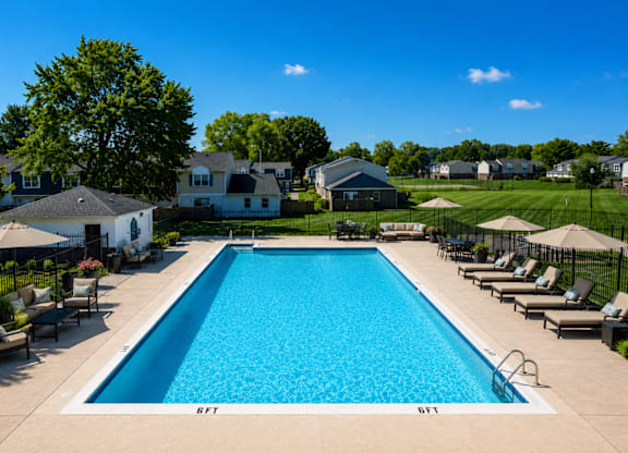 A large swimming pool surrounded by lounge chairs and umbrellas.