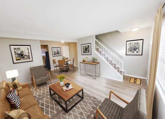 Living room with a couch and two chairs next to the dining area in a townhouse. 