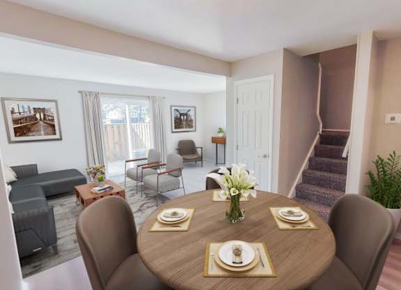 Circular dining table in front of the stairs while next to the living room area with sliding glass doors. 