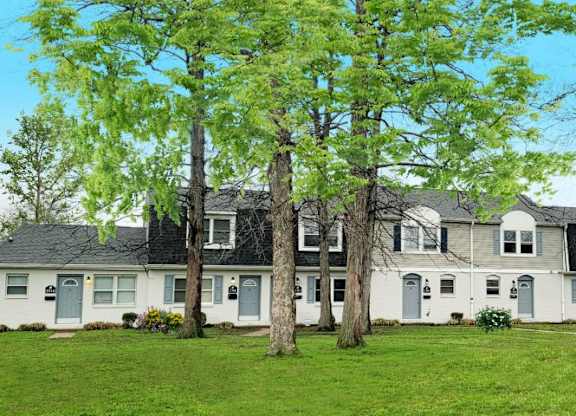 Exterior of townhomes with a large front yard and several trees. 