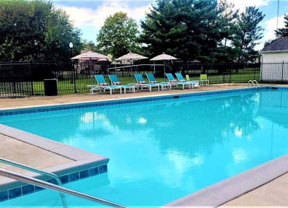 Fenced-in outdoor pool with several lounge chairs. 
