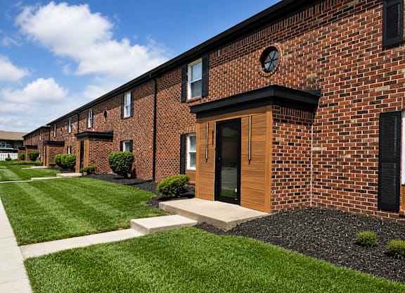 A row of red brick houses with green lawns in front.