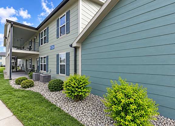 A blue house with a balcony and a small garden in front.
