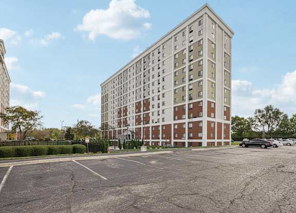 A tall building with a parking lot in front of it.