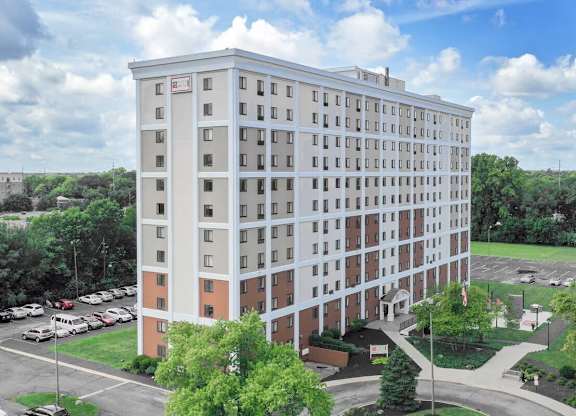 A large white hotel with a parking lot in front.