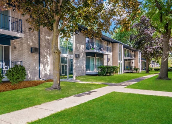 A tree in front of a building with a walkway in between.