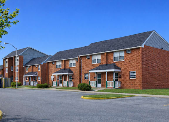 A large brick apartment building with a parking lot in front.