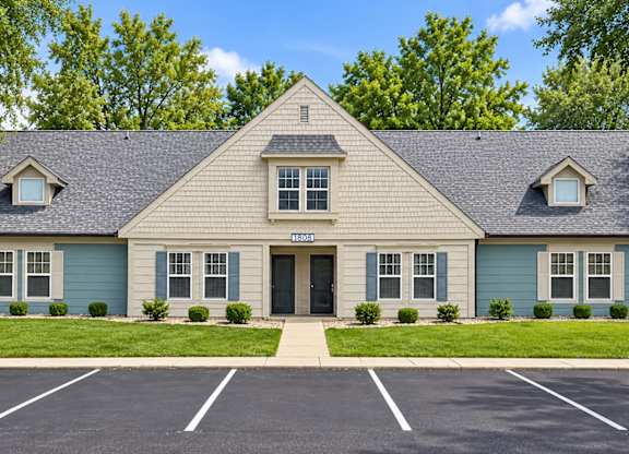 A small building with a triangular roof and a parking lot in front.