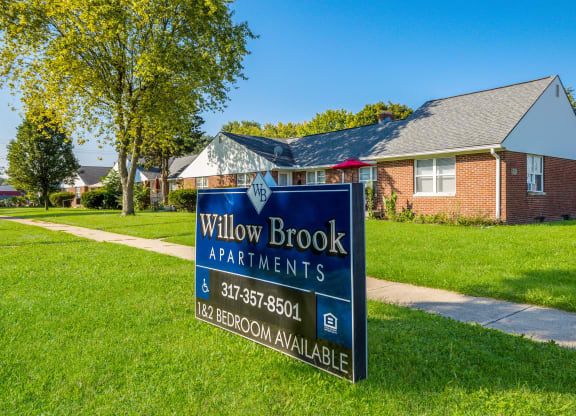 a sign for willow brook apartments in front of a house